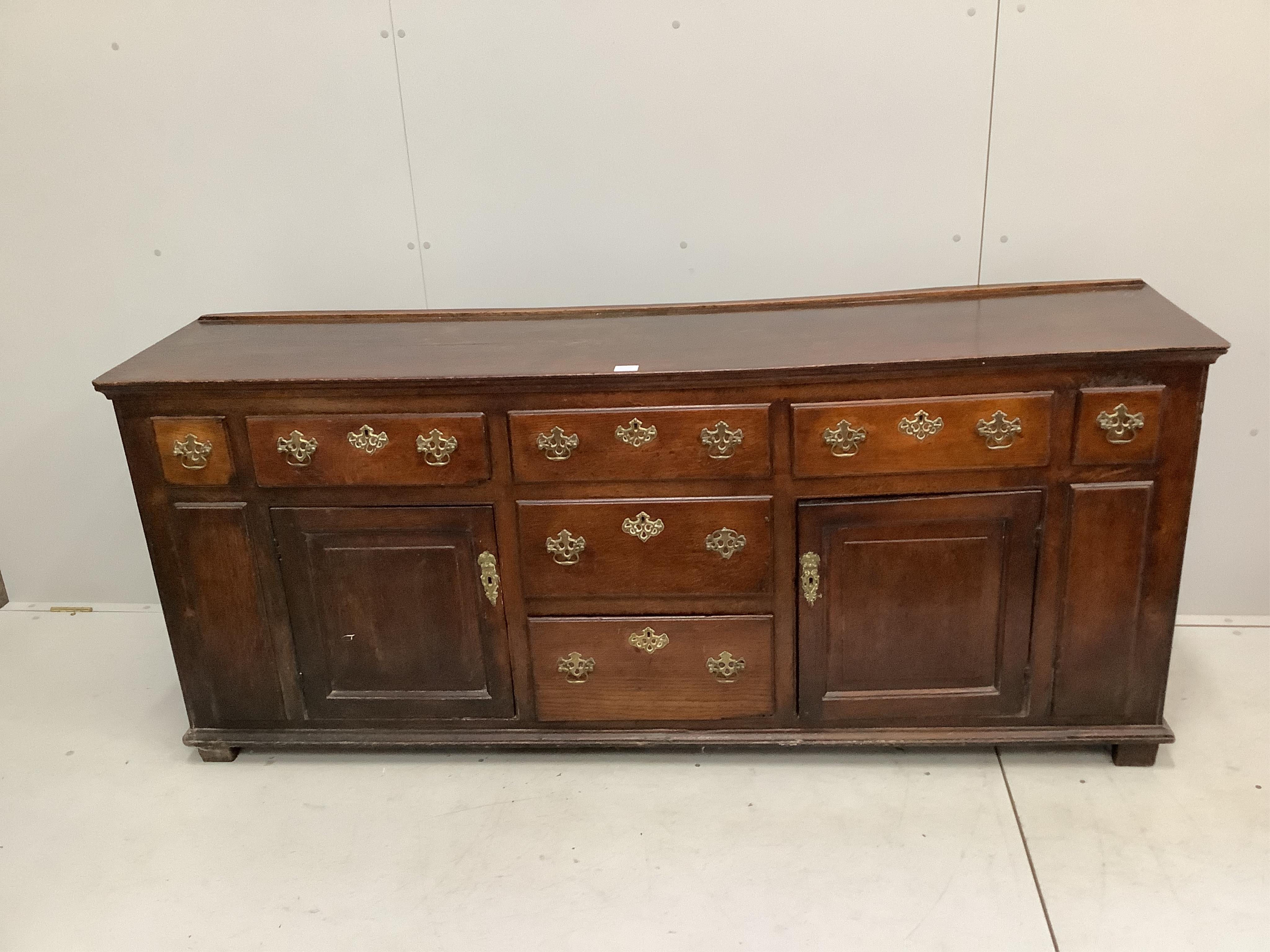 A mid 18th century oak low dresser, fitted seven small drawers, flanked by fielded panelled cupboards, width 192cm, depth 48cm, height 81cm. Condition - fair